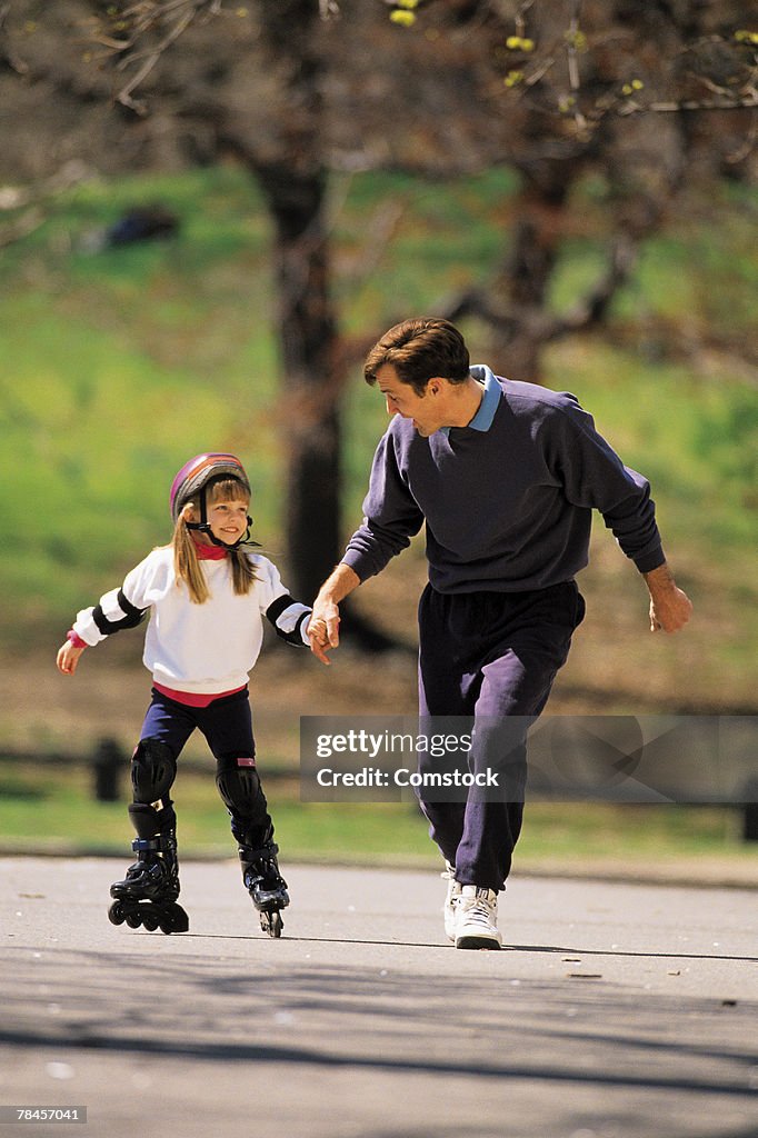 Father helping daughter on inline skates