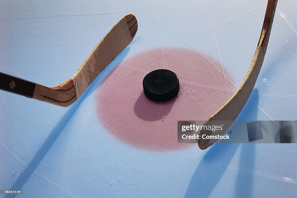 Ice hockey puck and sticks in face-off