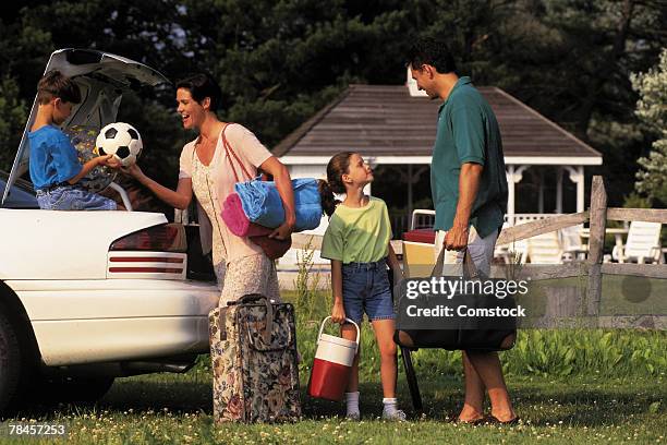 family unpacking car for vacation - soccer mum stock-fotos und bilder