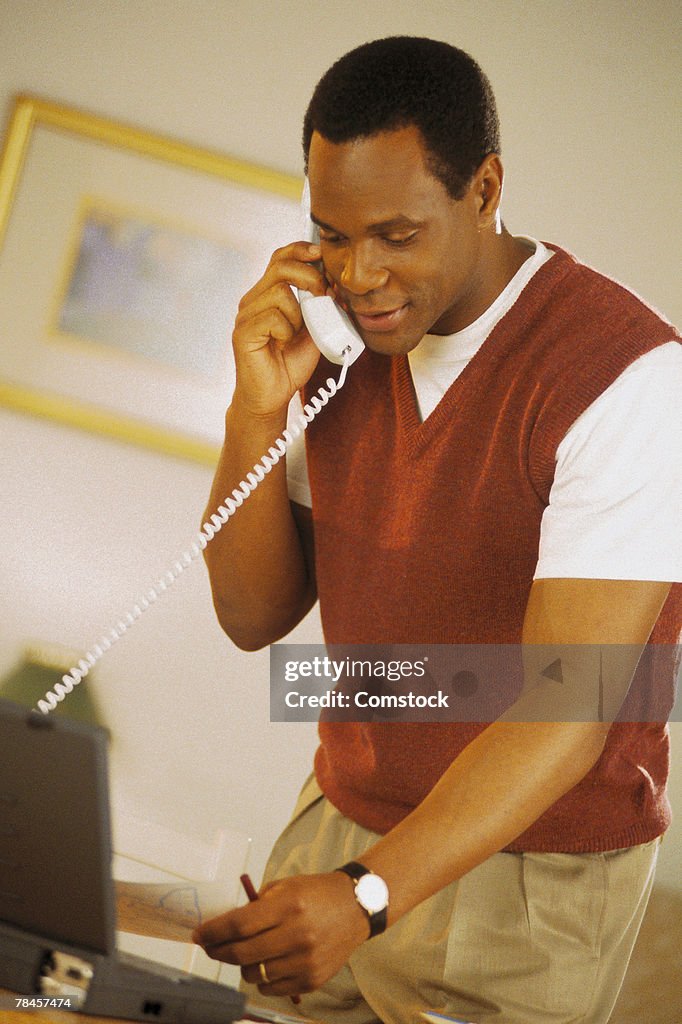 Man using laptop and talking on telephone