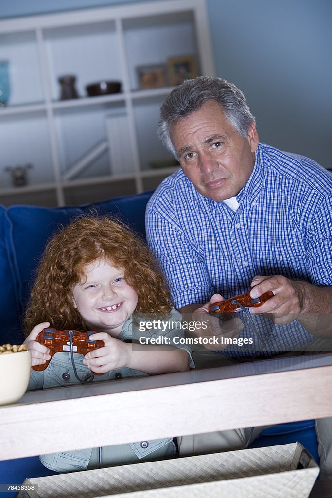 Grandfather and granddaughter playing video game