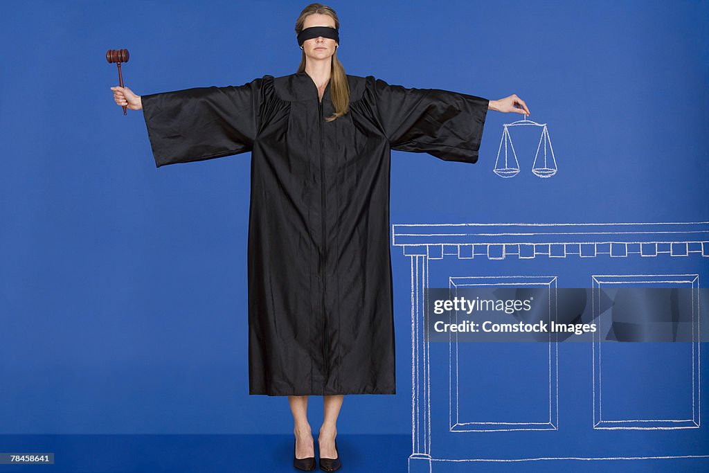 Blindfolded judge holding gavel and scales