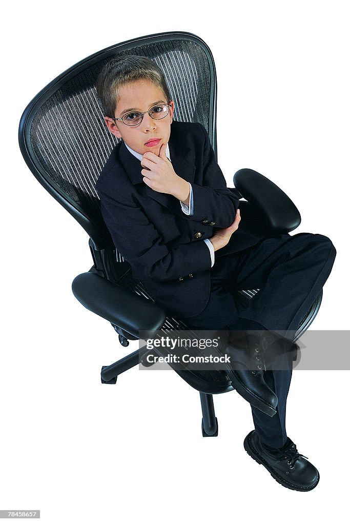 Boy in office chair dressed as businessman