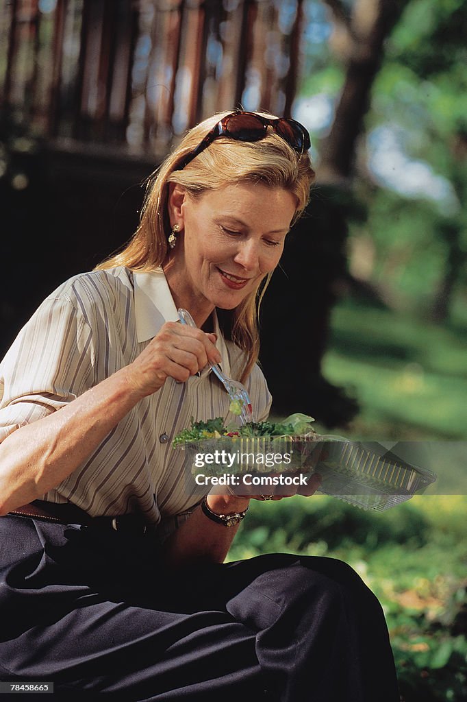 Woman sitting outdoors eating a salad