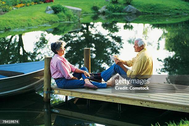 couple sitting on a dock talking and sketching - grey pier stockfoto's en -beelden
