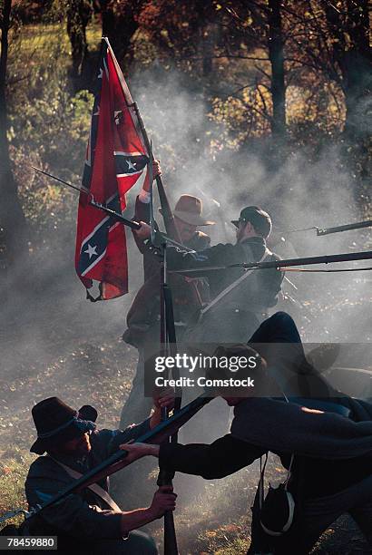 soldiers raising confederate flag during civil war reenactment - confederate flag stock-fotos und bilder