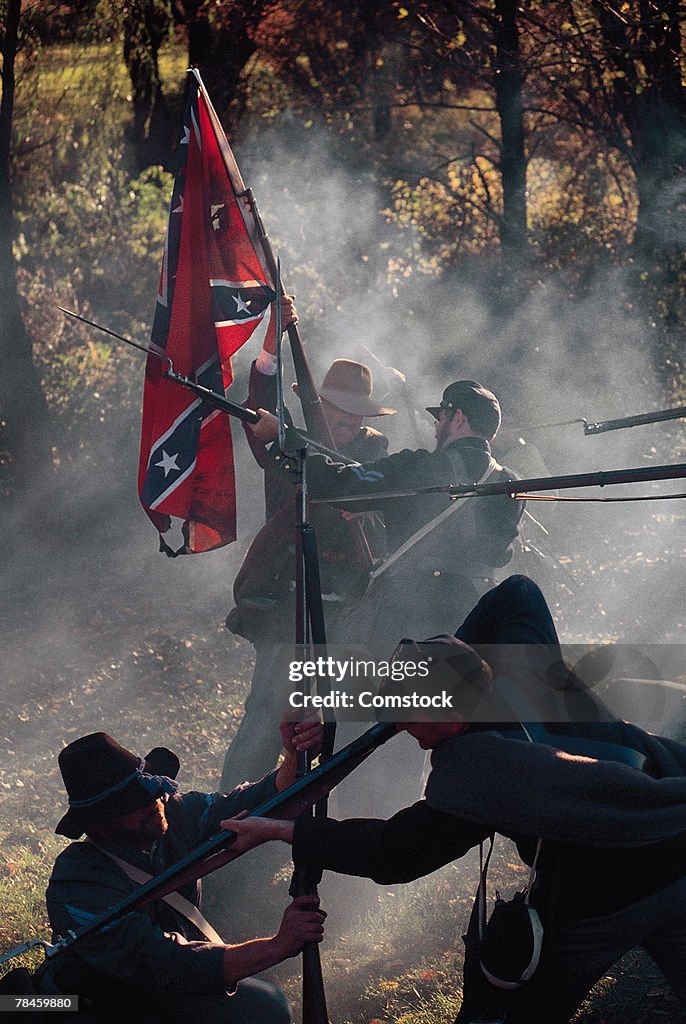 Soldiers raising confederate flag during Civil war reenactment