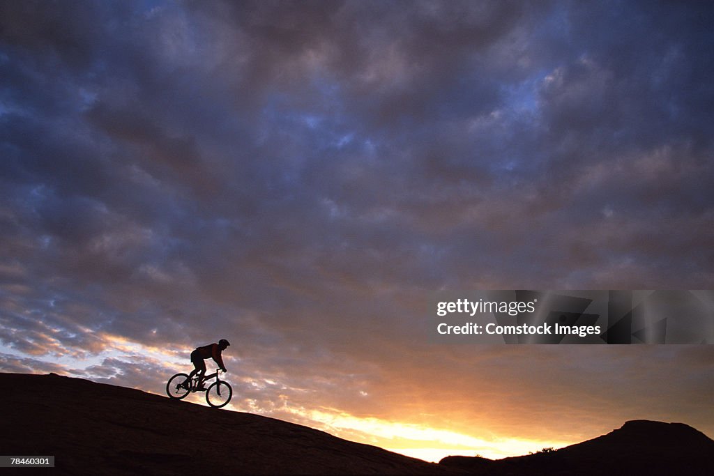 Man mountain-biking on slickrock at dawn