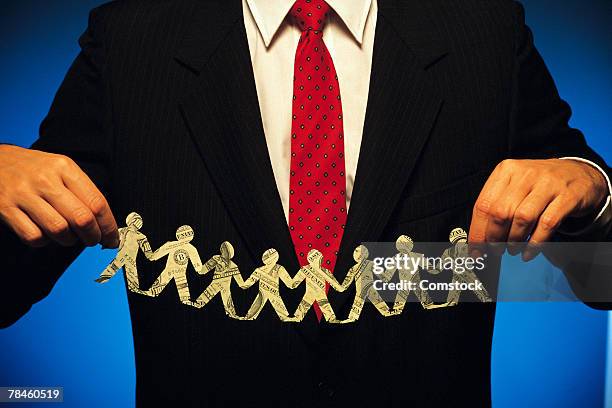 businessman holding up string of paper dolls made of money - dolly dollar stock pictures, royalty-free photos & images
