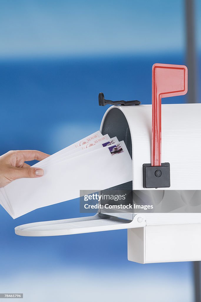 Woman removing envelopes from mailbox