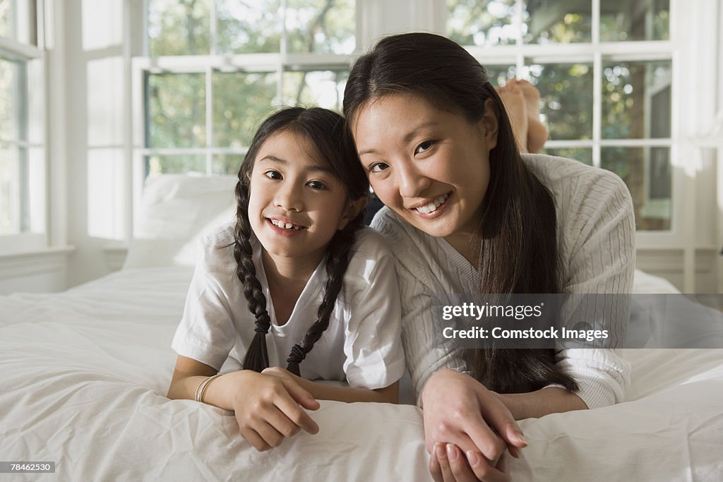 Mother and daughter lying down on a bed