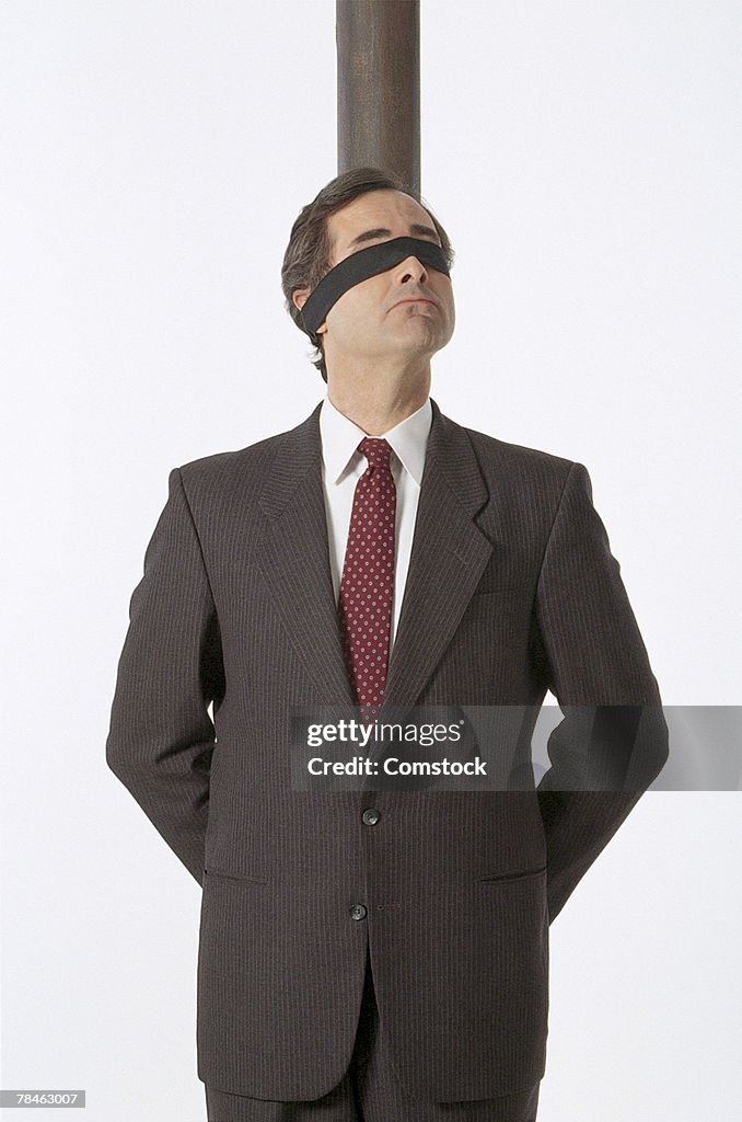 Blindfolded businessman tied to pole