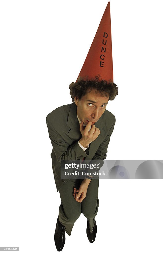 Scared businessman with dunce hat