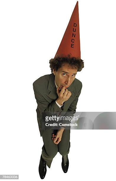scared businessman with dunce hat - dunce cap stock pictures, royalty-free photos & images