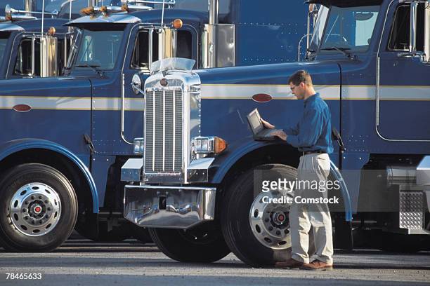 man with laptop computer standing next to big rigs - parking log stock pictures, royalty-free photos & images