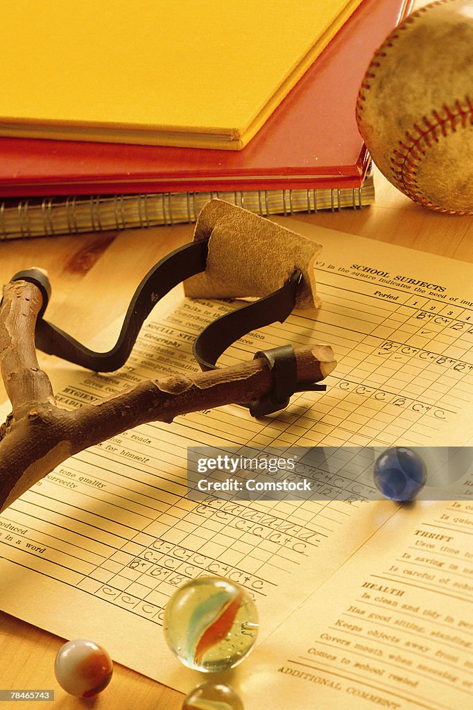 Report card with slingshot and marbles and baseball