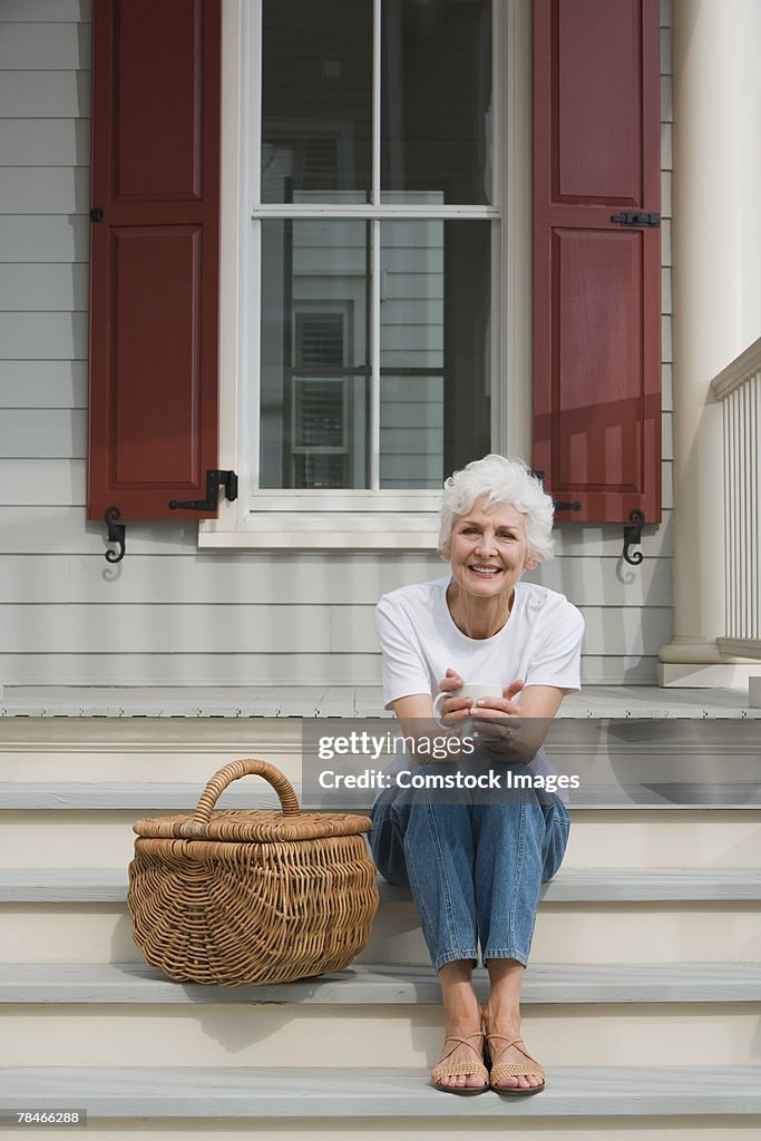 Smiling woman sitting on porch with picnic basket