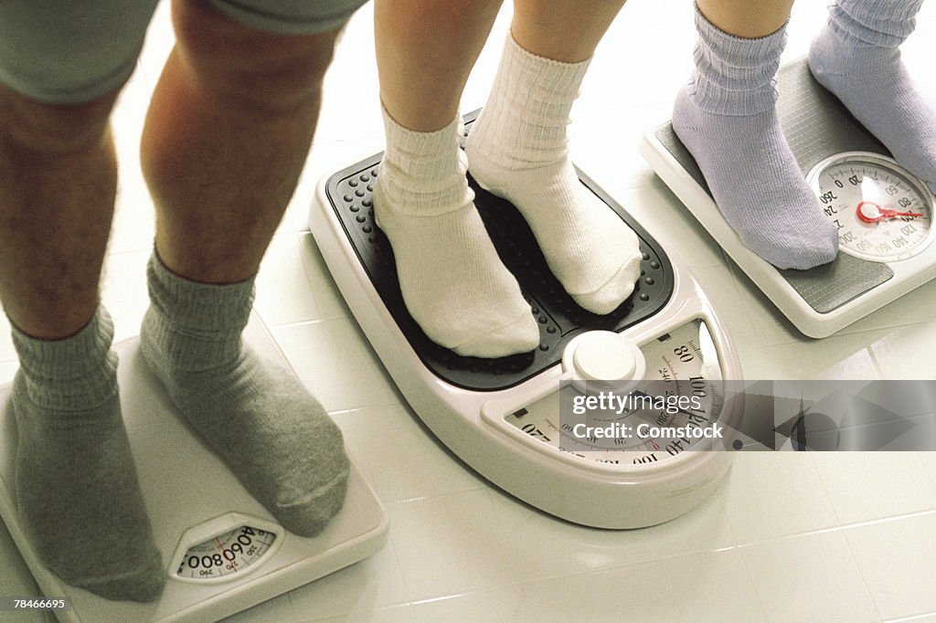 Three people on separate bathroom scales