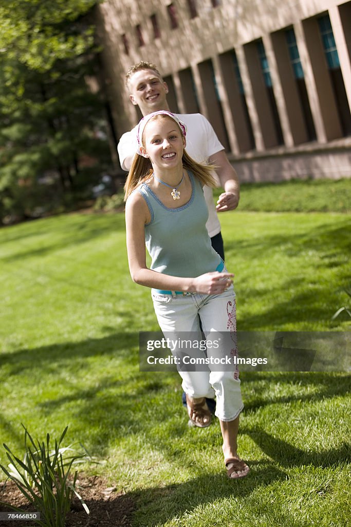 Young man and young woman running in grass