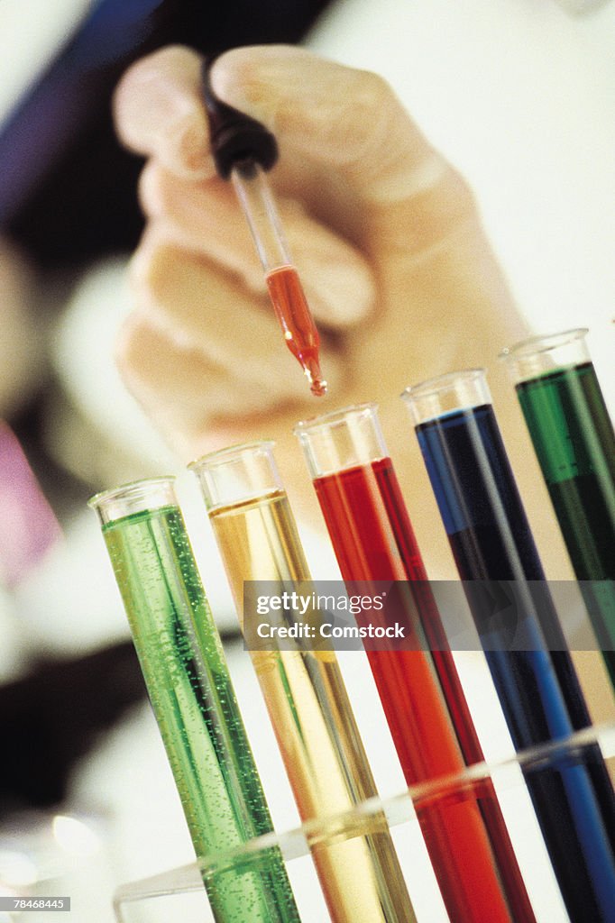 Eyedropper dripping liquid into test tubes