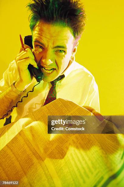 man screaming into telephone and holding stock pages - stock trader upset stock-fotos und bilder