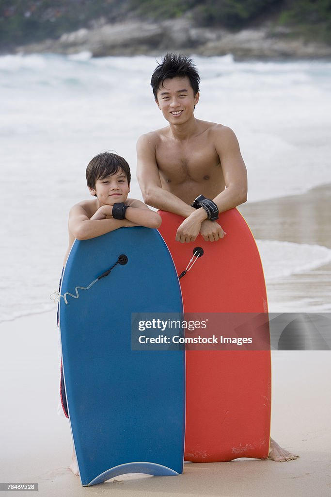 Father and son with body boards at beach