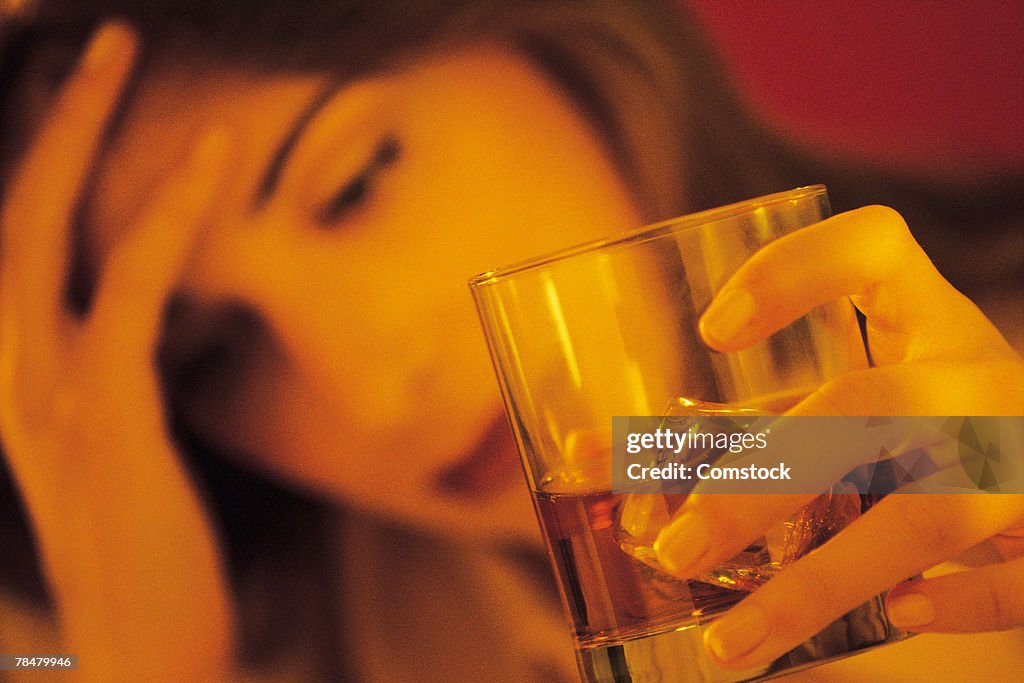 Stressed woman holding alcoholic drink