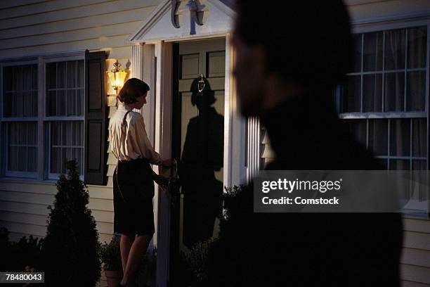 stalker spying on woman at front door - stalker stockfoto's en -beelden