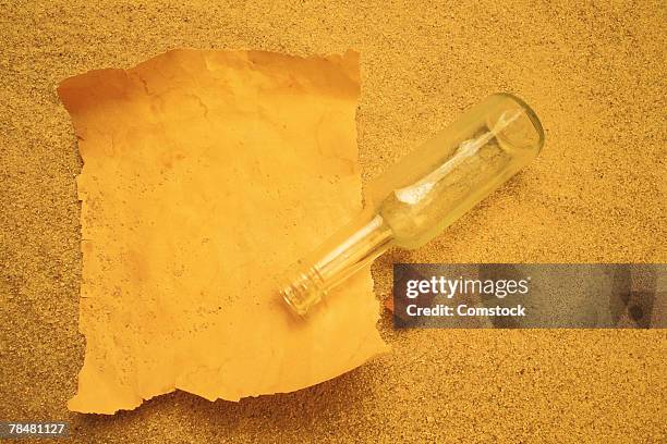 paper and bottle on sand - schiffbrüchiger stock-fotos und bilder