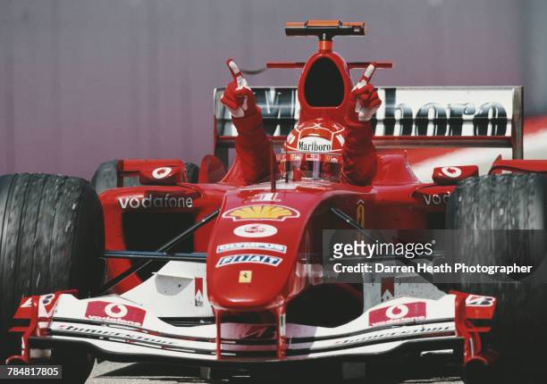 Michael Schumacher of Germany driving the Scuderia Ferrari Marlboro Ferrari F2004 Ferrari V10 with his arms raised from the cockpit celebrates...