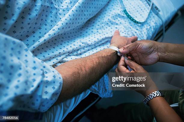 person putting id wristband on patient's arm - bracelet d'identification photos et images de collection