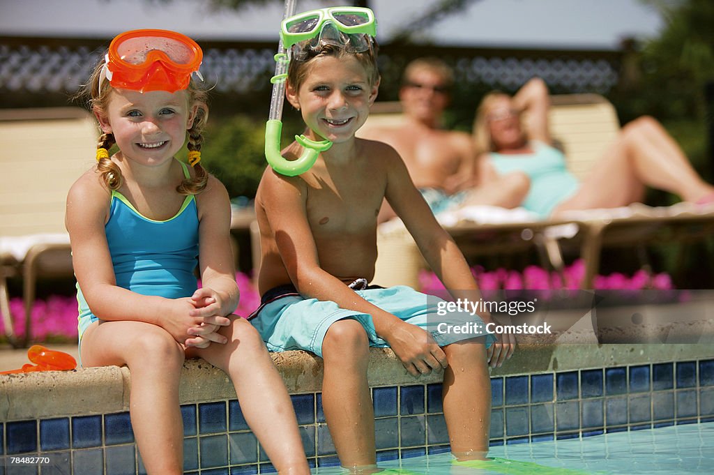 Happy children sitting on poolside