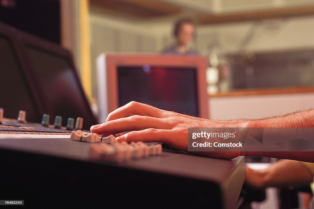 Hands of producer on mixing board in recording studio