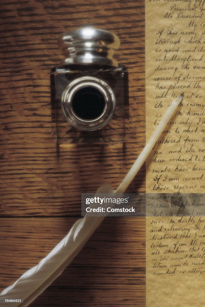 Quill with inkpot and handwriting on parchment