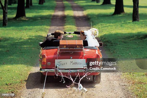 bride and groom driving away in car - brautpaar rückenansicht stock-fotos und bilder