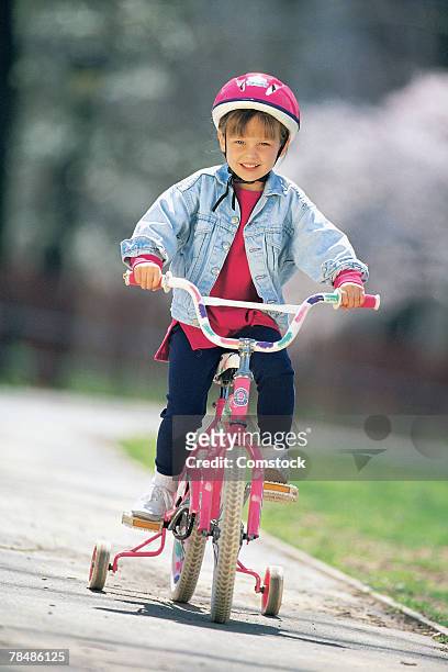 girl riding a bicycle - training wheels stock pictures, royalty-free photos & images
