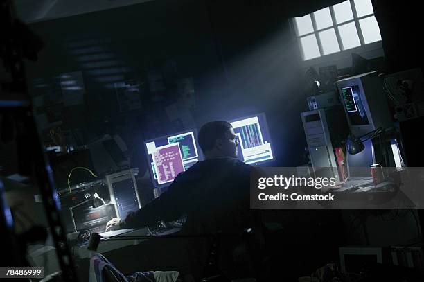 man working on computers in a dark room - dark lab room stock pictures, royalty-free photos & images