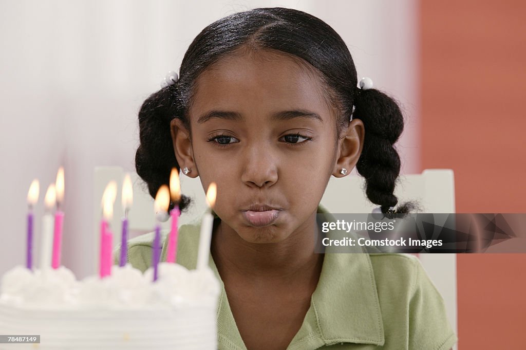 Girl frowning behind birthday cake