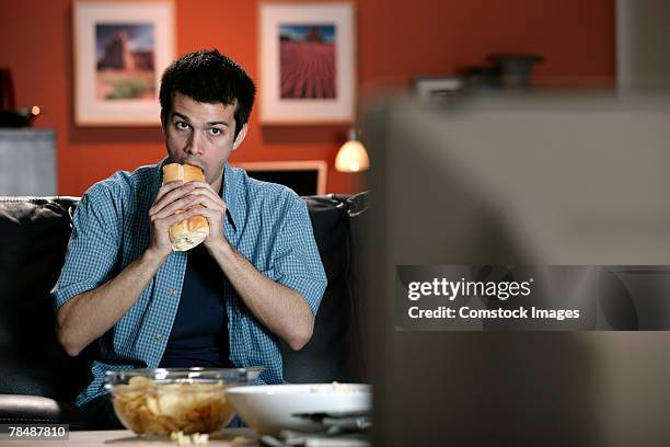 man eating sandwich and watching television - sub sandwich stock pictures, royalty-free photos & images