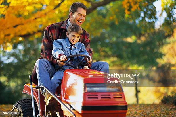 father and son on tractor mower - lawn tractor stock pictures, royalty-free photos & images