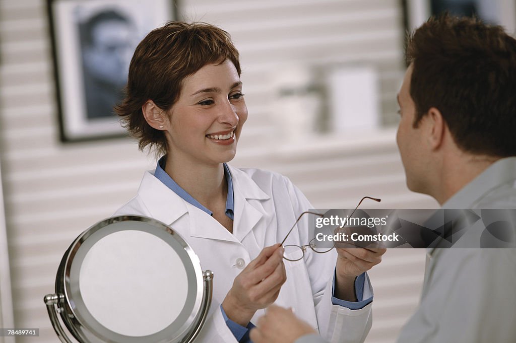 Woman helping man choose glasses