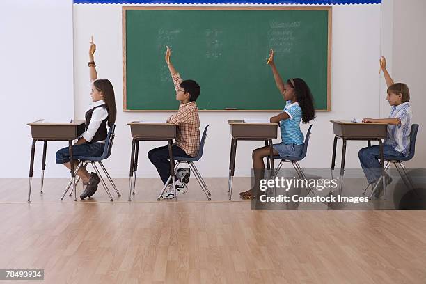 children raising their hands in classroom - student sitting in desk side view stock pictures, royalty-free photos & images