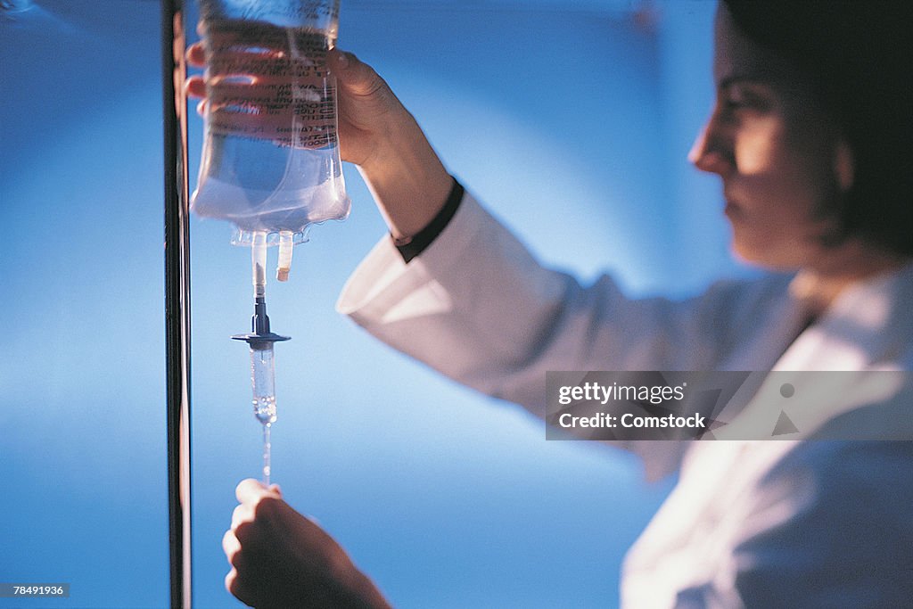 Woman medical professional adjusting an IV bag