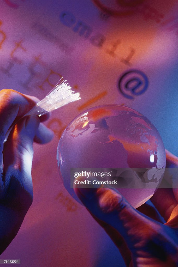 Hands holding fiber optics and a globe