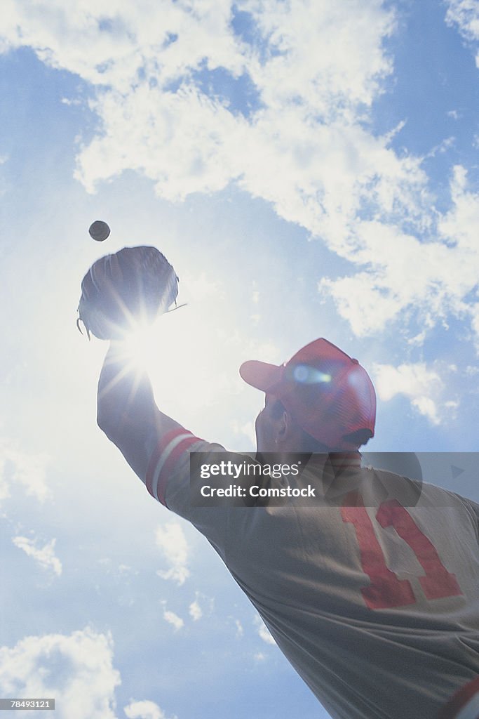 Baseball player catching ball with sun in his eyes