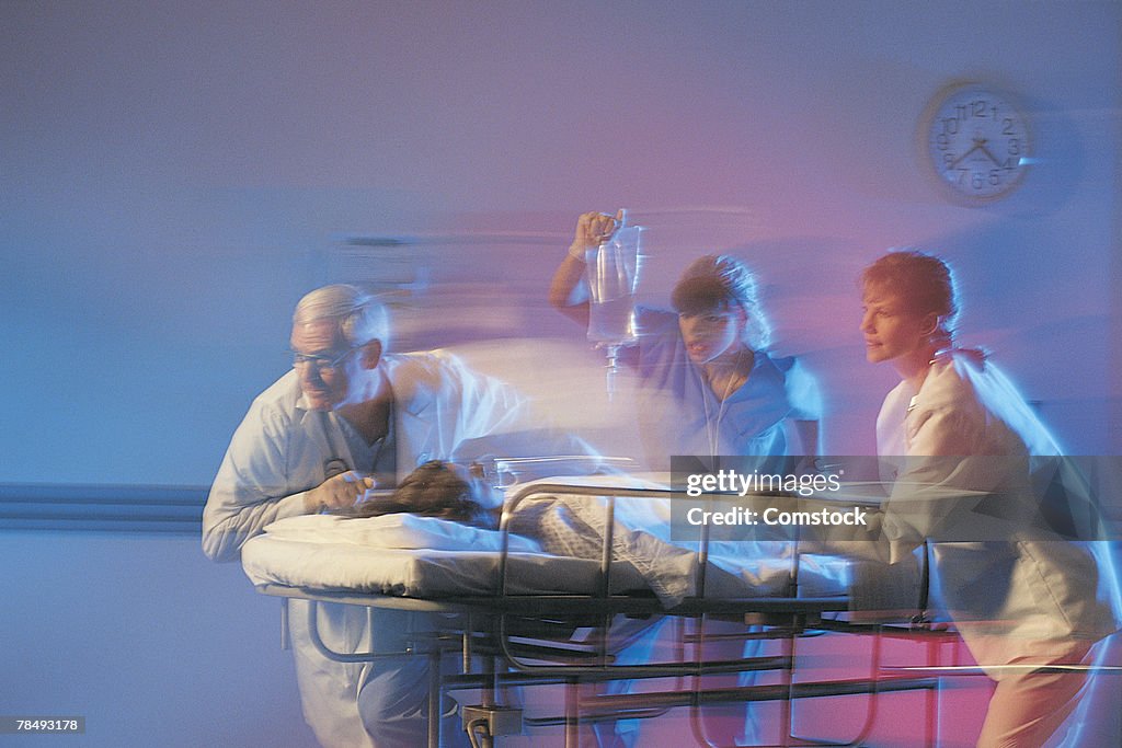 Doctors rushing patient through hospital corridor