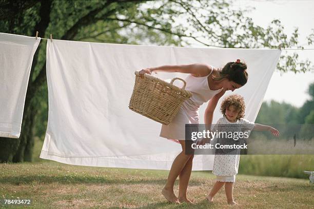 mother and daughter with laundry on clothesline - washing basket stock-fotos und bilder