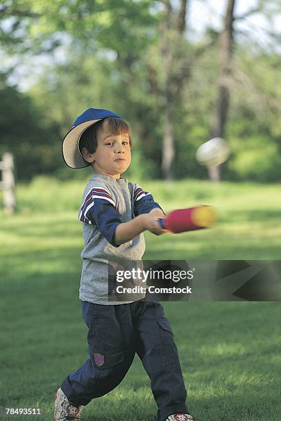 boy hitting baseball in backyard - backyard baseball stock-fotos und bilder