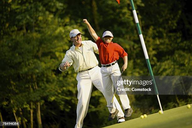 father and son celebrating while playing golf - golf day stock pictures, royalty-free photos & images