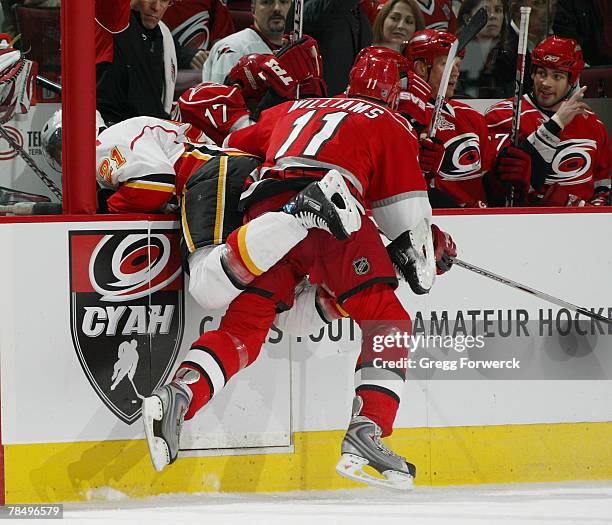 Justin Williams of the Carolina Hurricanes checks David Hale of the Calgary Flames into the Hurricanes' bench during a game on December 14, 2007 at...